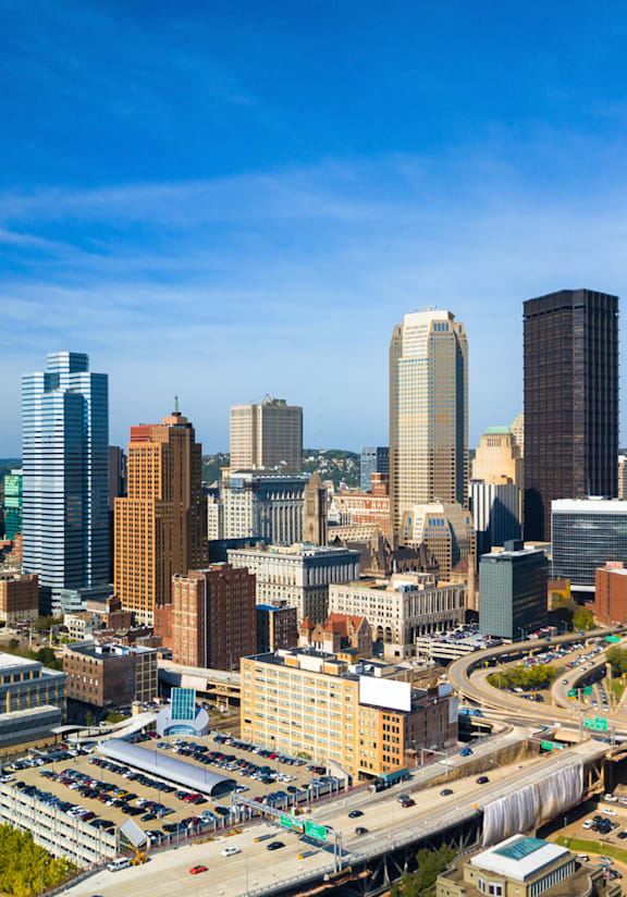 A cityscape with a mix of modern and older buildings, a bridge, and a clear sky.