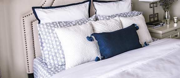 A white bed with blue pillows and a white headboard.