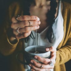 a woman drinking a cup of coffee with her hands