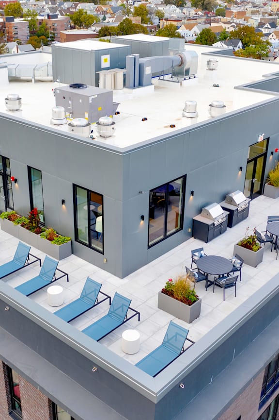 an aerial view of a building with blue lounge chairs and a table and chairs on the roof