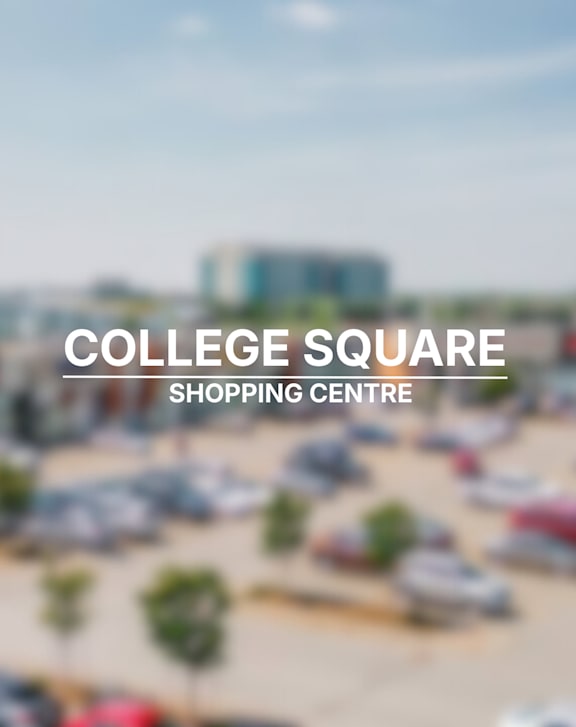 A large building with a red roof and a sign that says "Ladbrokes" in front of a parking lot.