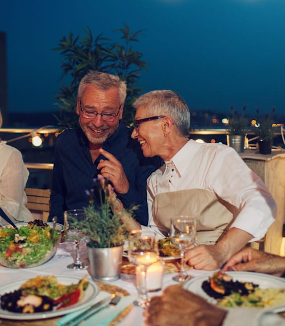 Two men are sitting at a dinner table with plates of food in front of them.