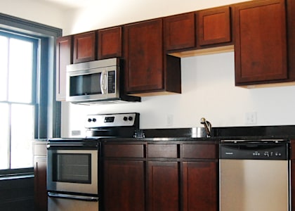 A kitchen with wooden cabinets and a black dishwasher.