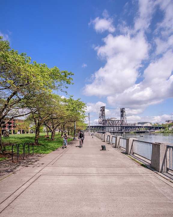 Man and Woman Riding Bikes Along River in Portland, Oregon