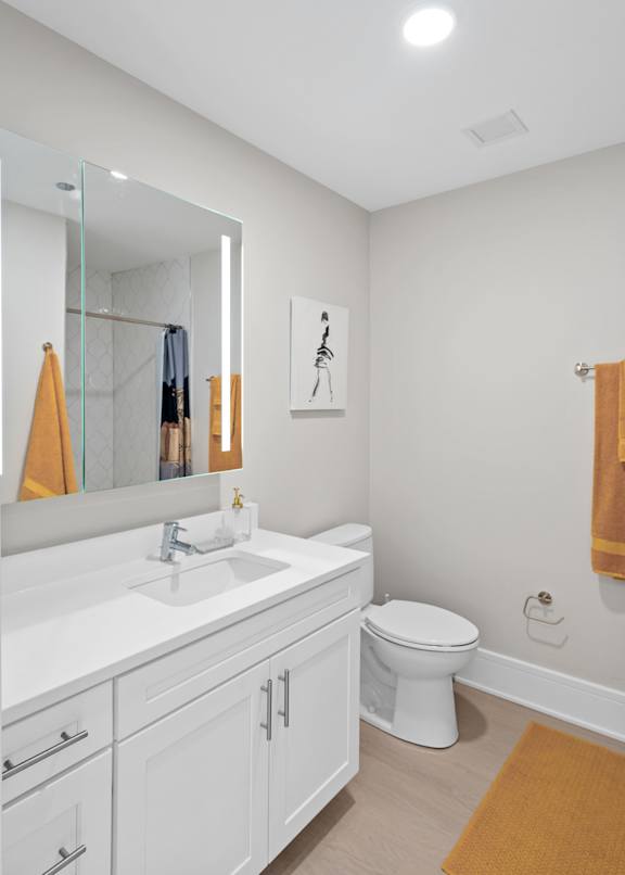 A bathroom with a toilet, sink, and mirror.