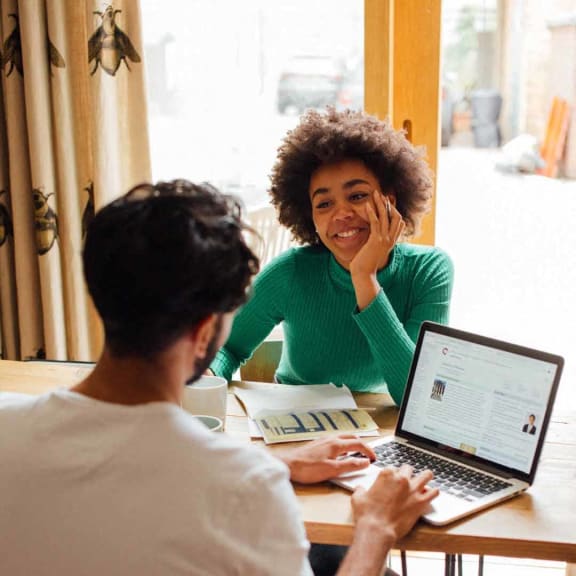 two people sitting at a table with a laptop