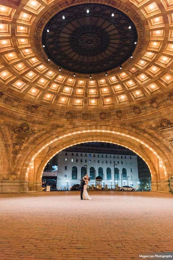 A couple posing for a photo in a circular archway with lights. at The Pennsylvanian Apartments, Pittsburgh, Pennsylvania