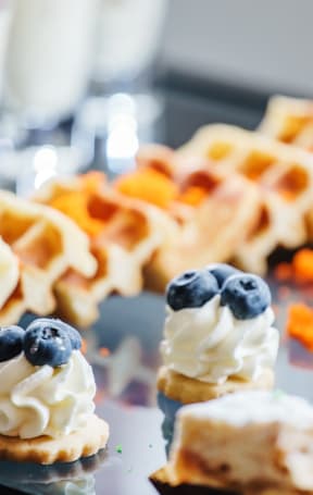 A dessert with whipped cream and blueberries is in the foreground.