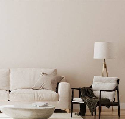 A living room with a white couch, a wooden chair, a white table, and a potted plant.