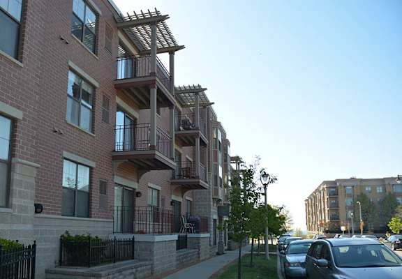 A row of apartment buildings with cars parked in front.
