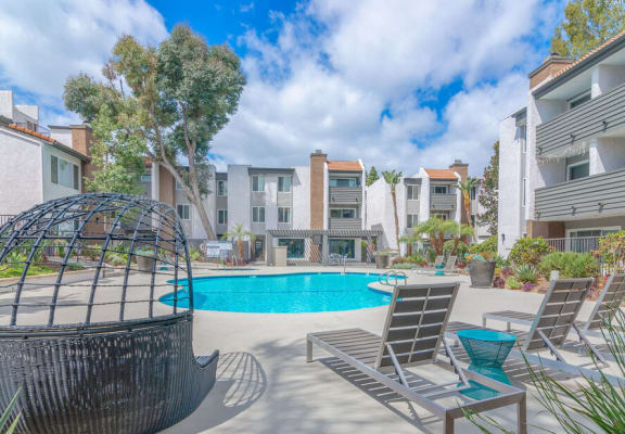 a pool with chairs and a hammock in front of an apartment building at City View Apartments at Warner Center, Woodland Hills California