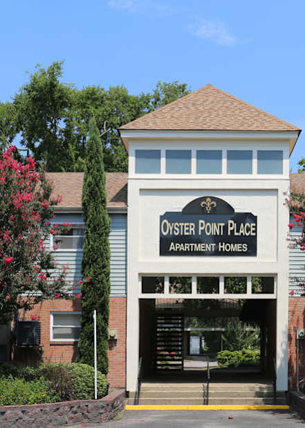 The entrance to a building with a sign that says "Oyster Point Place Apartments".