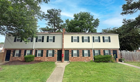 A two-story house with a red door and green bushes.
