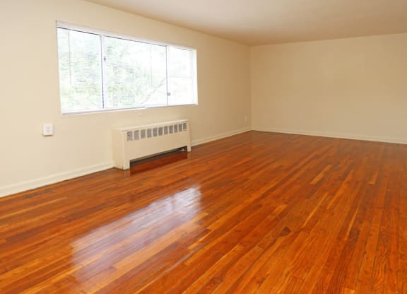 an empty living room with wooden floors and a window