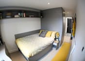 Thumbnail 5 of 8 - a bedroom with a bed and a nightstand