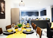 Thumbnail 4 of 8 - a long dining table with a kitchen in the background