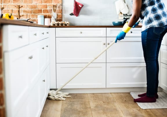 a woman is mopping the floor in the kitchen