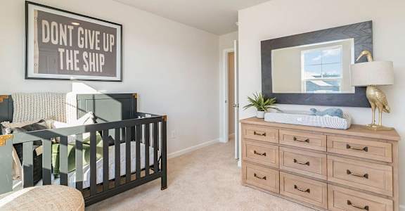 A nursery room with a crib, changing table, and a poster that says "Don't give up the ship".