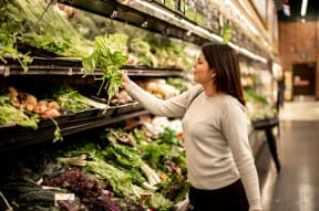a woman shopping for vegetables in a grocery store