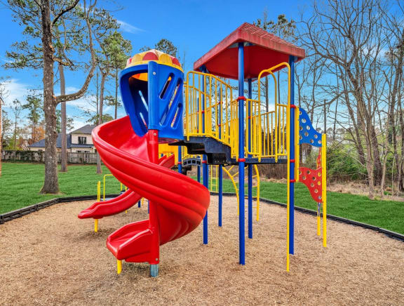 a playground with a red slide and blue and yellow equipment