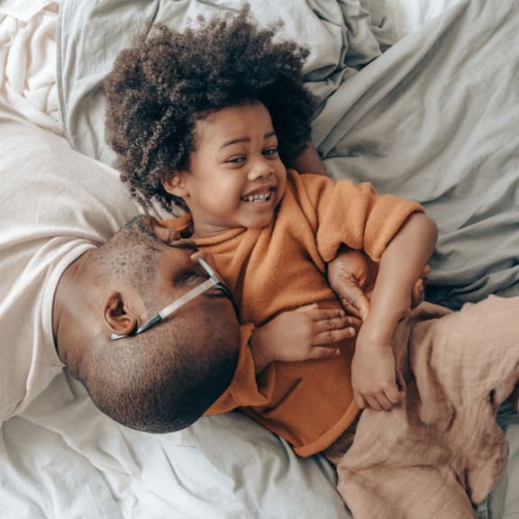 a man and a child laying in bed with a thermometer