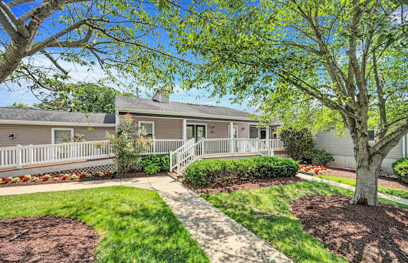 a house with a white fence and a tree in front of it