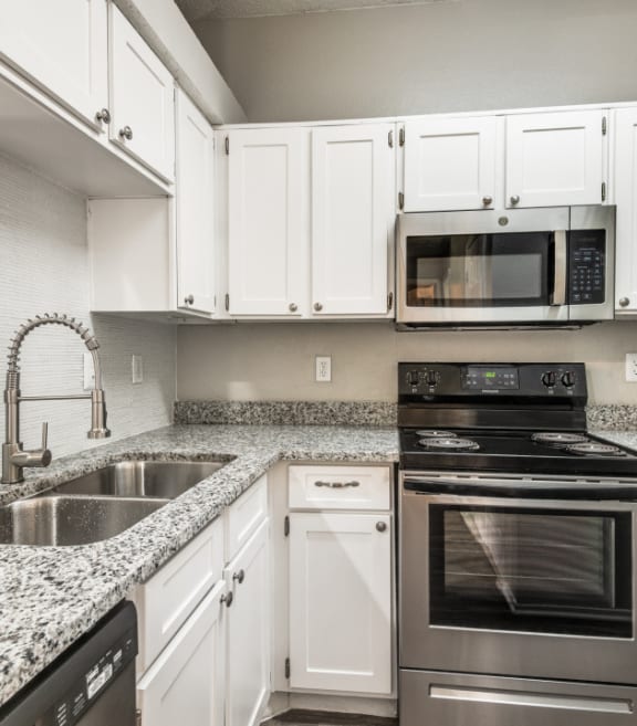 a kitchen with granite counter tops and stainless steel appliances at Foxborough Apartments, Irving, TX