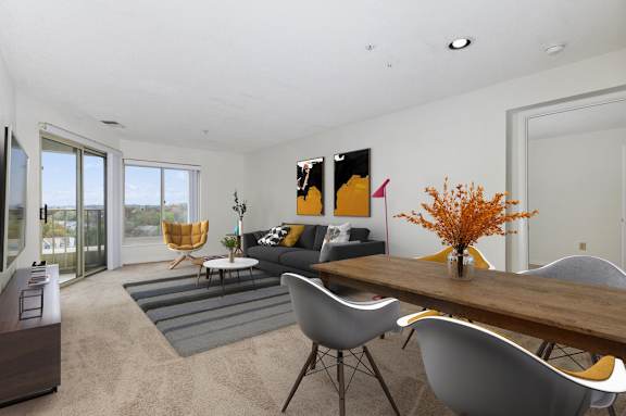A living room with a grey sofa, a grey chair, a wooden table and a grey rug.