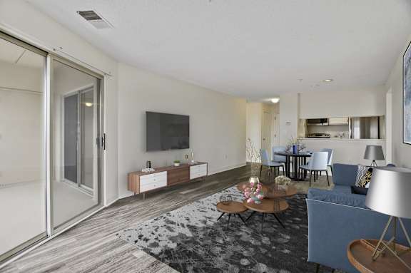 A living room with a grey sofa, a wooden coffee table, and a television on the wall.