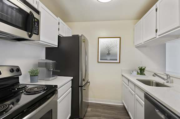 A kitchen with black and white appliances and a framed picture on the wall.