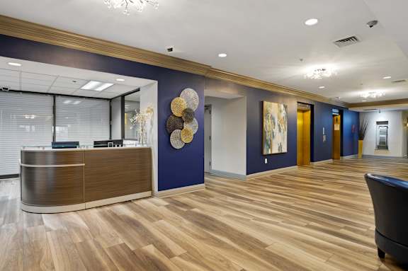 A reception area with a wooden floor and a brown reception desk.