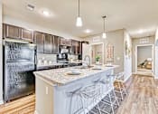 Thumbnail 23 of 34 - an open kitchen with a bar with stools and a refrigerator at the flats at sundown luxury apartments in north port florida