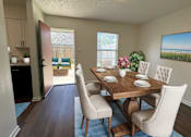 Thumbnail 1 of 15 - A dining room with a wooden table and chairs.