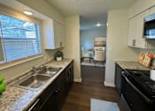 Thumbnail 6 of 15 - A kitchen with a black stove top oven and a sink with a faucet.
