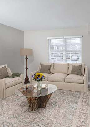 A living room with a glass coffee table and a couch.