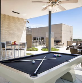 a pool table in a patio area with a ceiling fan