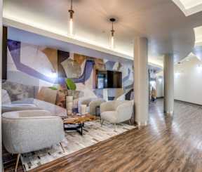 A modern living room with a wooden floor and a large mural on the wall.