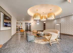 A modern living room with a large circular light fixture and a grey carpet.