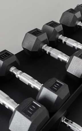 A set of dumbbells are arranged on a black surface.