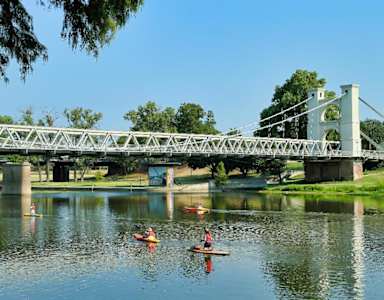 A bridge over a body of water with people kayaking underneath.