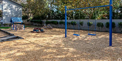 A playground with a blue swing set and a slide.