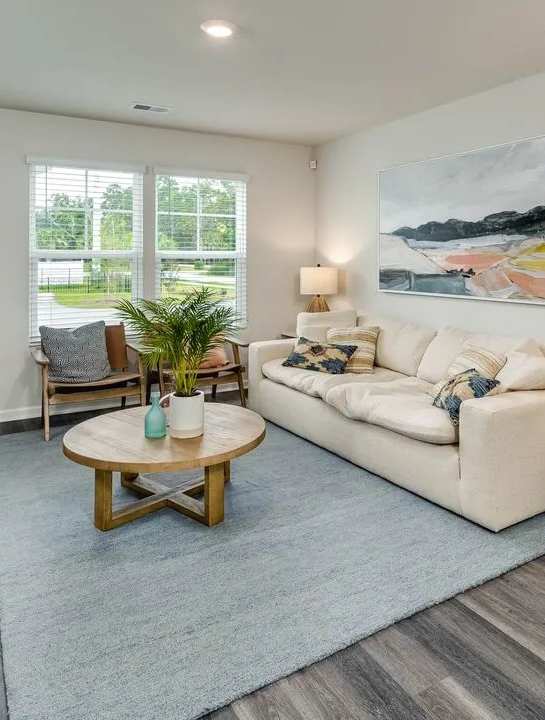 A living room with a white couch, a wooden coffee table, and a painting on the wall.