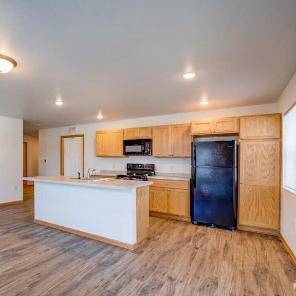 A kitchen with a white counter and a black fridge.