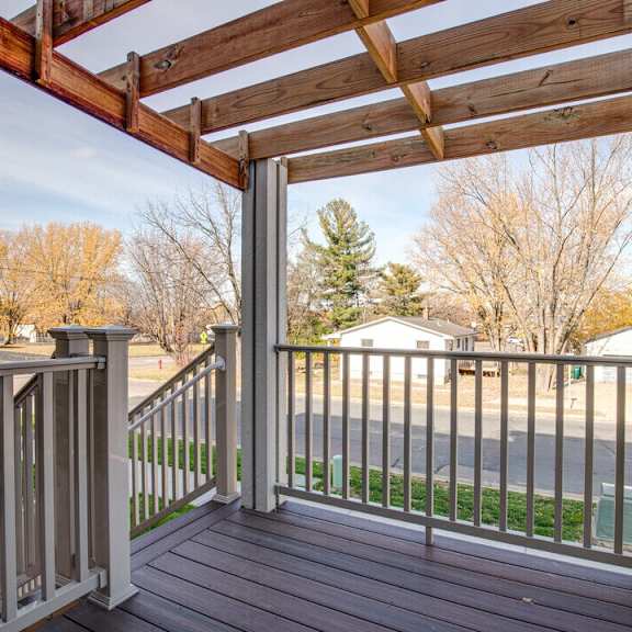 A wooden deck with a pergola and a metal railing.