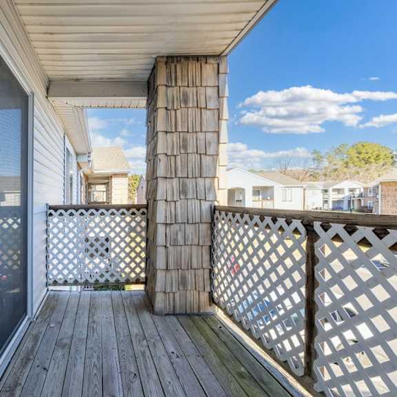 A wooden deck with a lattice fence and a glass door leading to a balcony.