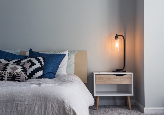a bedroom with a bed with blue and white bedding and a white nightstand with a