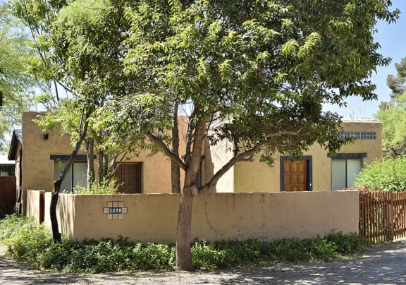 A tree in front of a house with a wall that has the numbers 3226 on it at San Xavier Casitas, Tucson, 85716