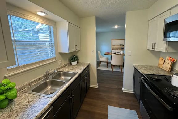 A kitchen with a black stove top oven and a sink with a faucet.