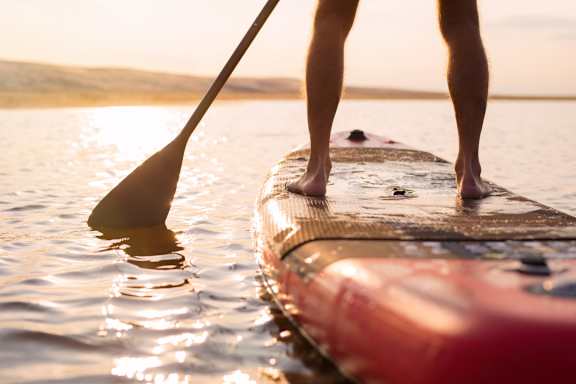 Person Paddleboarding on Lake During Sunset