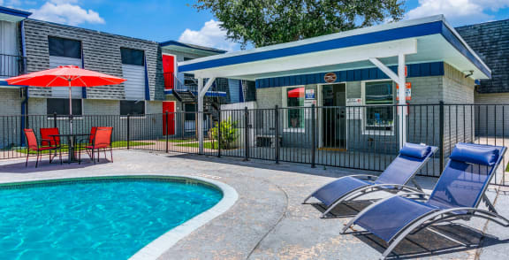 our apartments have a pool and a patio with chairs and a umbrella